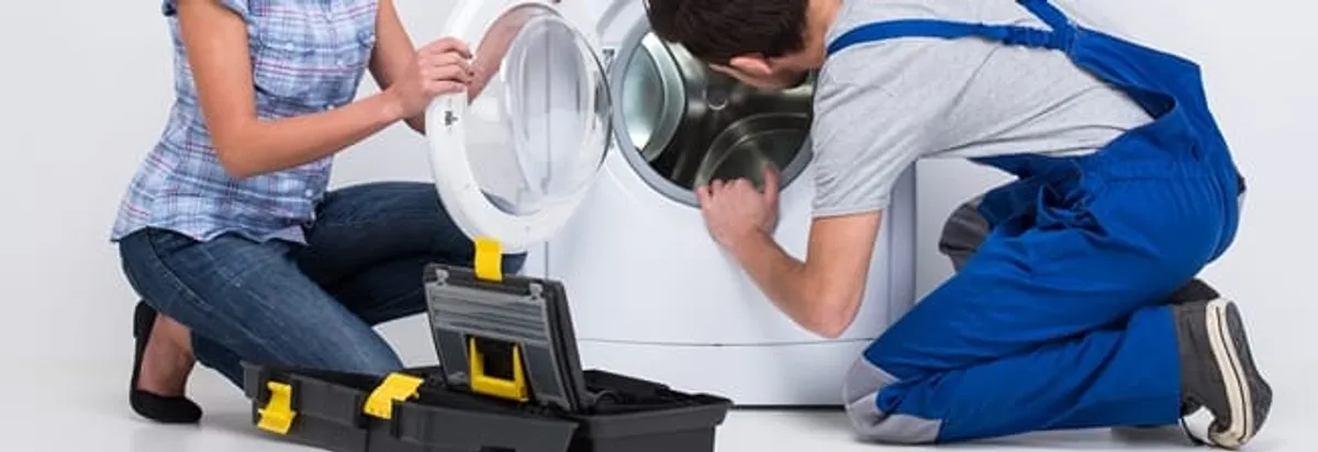 Washer repair technician inspecting a front-load washing machine with tools in Knoxville, TN