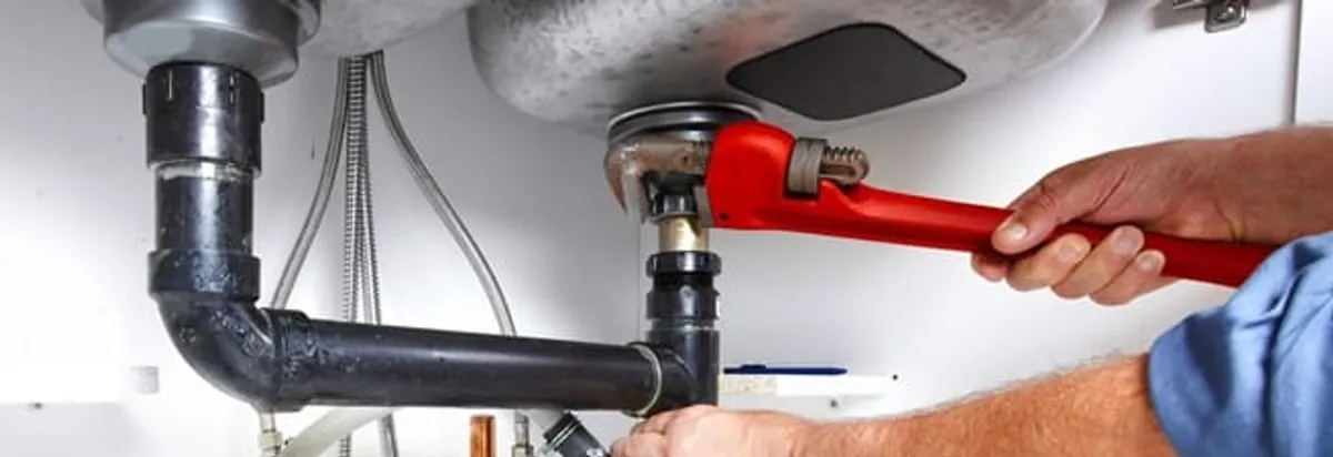Garbage disposal repair technician tightening the sink drain and disposal connection in Knoxville, TN