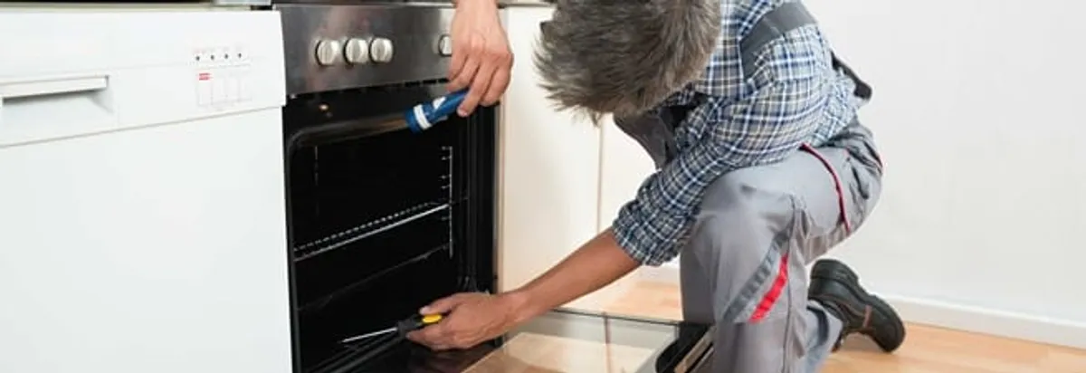 Oven repair technician inspecting and servicing an electric oven in Knoxville, TN