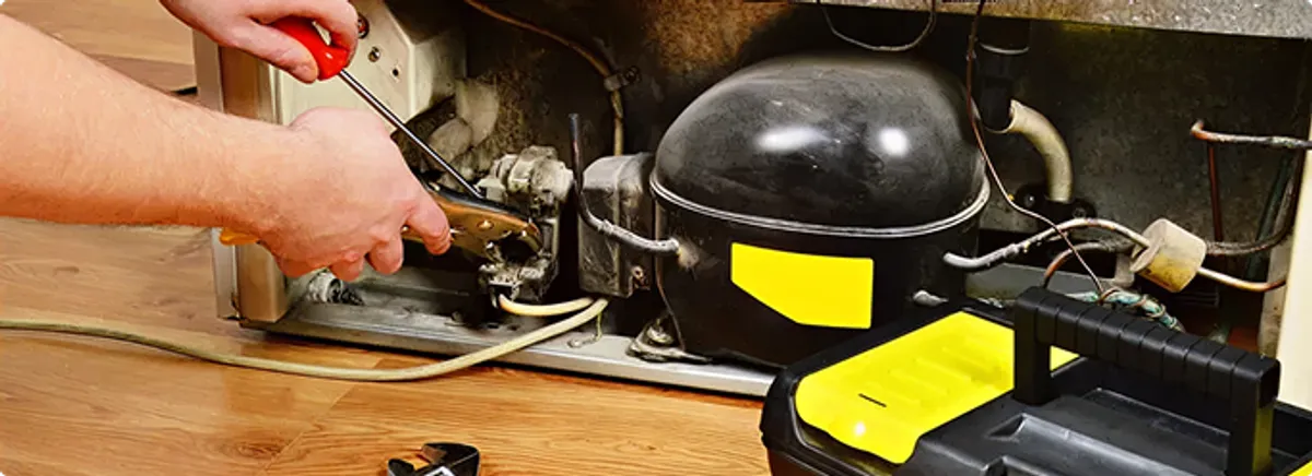 Refrigerator repair technician fixing the compressor and wiring in Knoxville, TN