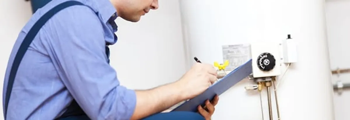 Water heater repair technician inspecting the unit and recording service notes in Knoxville, TN